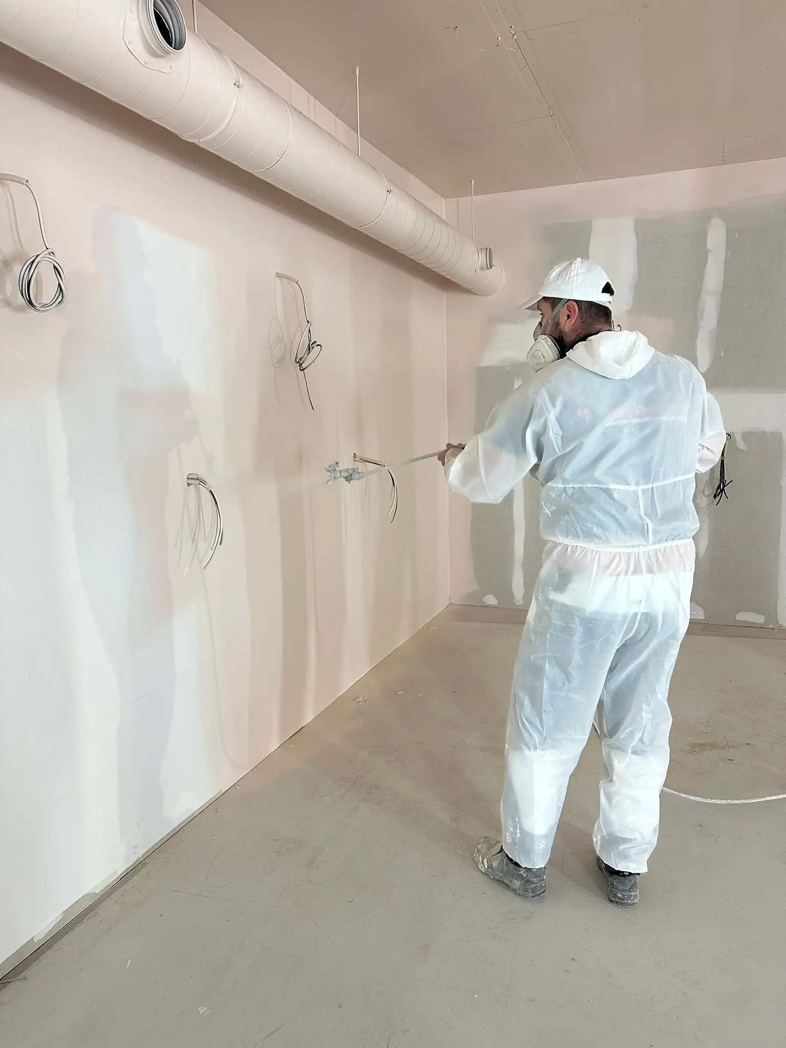Schilder spuit met een airless installatie een wand in een nieuwbouwpand