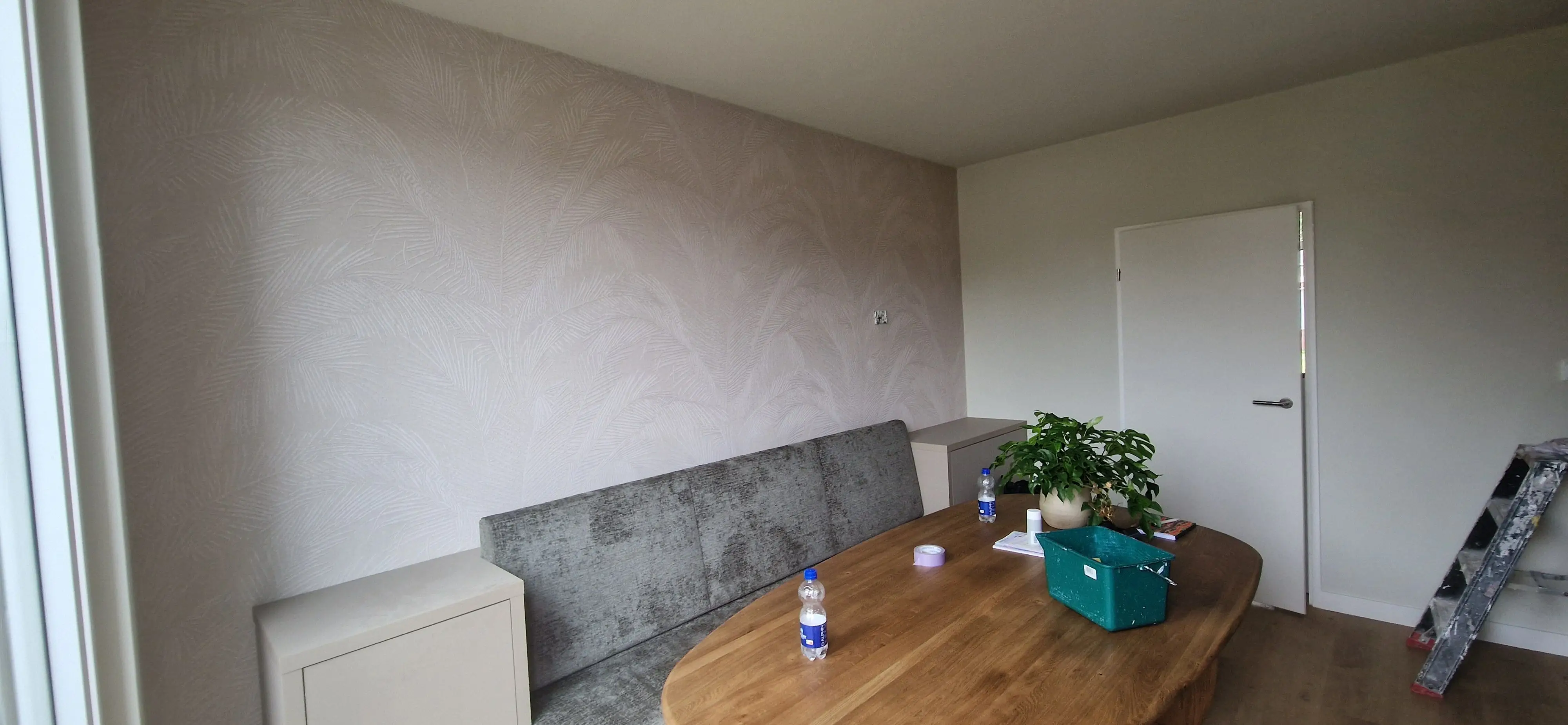 Eethoek met een wand vol vliesbehang met een licht bladpatroon