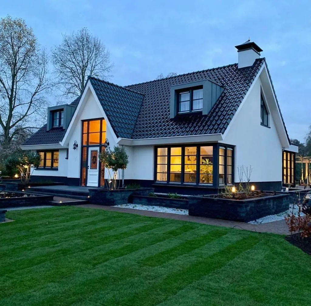 Vrijstaand woonhuis in de schemering met witte gevel en antracietgrijze kozijnen